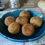 Sette polpette di pane dorate e croccanti, servite su un piatto blu. Perfette per uno spuntino gustoso.