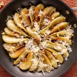 Finocchi in padella dorati, guarniti con scaglie di formaggio e noci croccanti. Un piatto semplice e saporito.