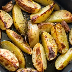 Patate al forno dorate e croccanti, condite con rosmarino e aglio, pronte per essere gustate.