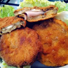 Cordon bleu di melanzane dorati e croccanti, ripieni di prosciutto e formaggio filante, serviti su un letto di lattuga fresca.