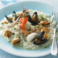 Un cremoso risotto alla pescatora, ricco di cozze, gamberi e calamari, pronto per essere gustato.