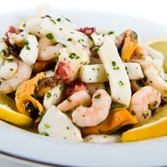 Deliziosa insalata di mare con gamberi, calamari, polpo e cozze, condita con prezzemolo e limone.