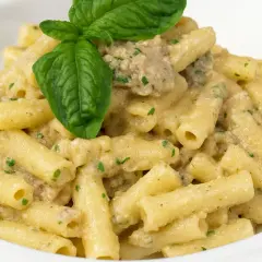 Un piatto invitante di pasta con melanzane in bianco cremosa, guarnito con basilico fresco.