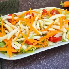 Deliziosa insalata di seppie con lattuga croccante, carote julienne e pomodorini freschi. Un piatto leggero e saporito.