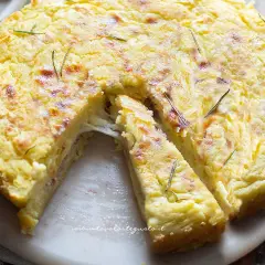 Torta salata con patate, filante e dorata, guarnita con rosmarino. Perfetta per un pranzo gustoso.