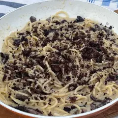 Spaghetti cremosi con olive nere e una spolverata di briciole scure, un'interpretazione audace della pasta alla cenere.