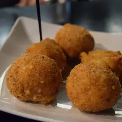 Deliziosi arancini di riso dorati e croccanti, serviti su un piatto bianco.