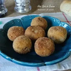 Sette polpette di pane dorate e croccanti, servite su un piatto blu. Perfette per uno spuntino gustoso.