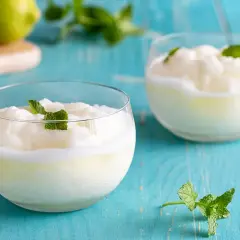 Due bicchieri di sorbetto al limone senza albume, guarniti con menta fresca, su un tavolo di legno blu.