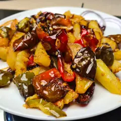 Un piatto invitante di **pipi e patate** saltate, con peperoni verdi e rossi croccanti e patate dorate, condite con spezie.
