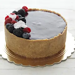Delizioso cheesecake ai frutti di bosco con copertura al cioccolato fondente, decorato con lamponi, mirtilli e more freschi.