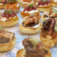 Varietà di antipasti di pesce su pane tostato: polpo grigliato, gamberi, tonno e salmone. Un'esplosione di sapori marini.