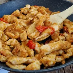 Straccetti di pollo saporiti cotti in padella con pomodorini e erbe aromatiche, pronti per essere gustati.