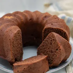 Un delizioso ciambellone al cioccolato, soffice e invitante, con una fetta tagliata che mostra la sua morbidezza.