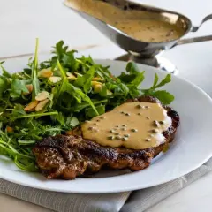 Un succulento filetto al pepe verde, nappato con la sua salsa cremosa, accompagnato da un'insalata fresca di rucola e mandorle.