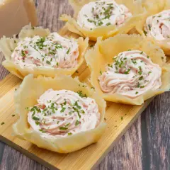Deliziosi cestini di parmigiano ripieni di crema rosa e guarniti con erba cipollina. Un antipasto elegante e gustoso.