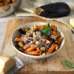 Piatto di pasta alla norma, un classico della ricetta della nonna, con melanzane, pomodoro e ricotta salata grattugiata.