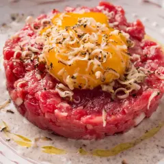 Tartare di manzo con tuorli d'uovo, cipolla e formaggio grattugiato. Un'idea su come condirla per un piatto gourmet.