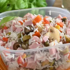 Insalata di riso colorata con prosciutto a cubetti, carote, olive, piselli e funghi, pronta per un pasto veloce.