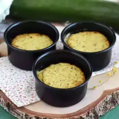 Tre deliziosi flan di zucchine appena sfornati in stampini neri, pronti per essere gustati.
