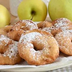 Frittelle di mele dorate e spolverate di zucchero a velo, pronte per essere gustate.