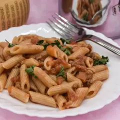Piatto di pasta con salsiccia e pomodoro, guarnito con prezzemolo fresco. Un classico della cucina italiana, pronto per essere gustato.
