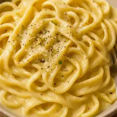 Un piatto invitante di pasta in bianco, condita con pepe nero macinato fresco e parmigiano grattugiato.