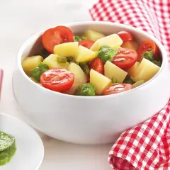 Deliziosa insalata di patate estiva con pomodorini e piselli, condita con un pesto fresco. Perfetta per un picnic o una cena leggera.
