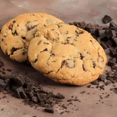 Due golosi cookies con gocce di cioccolato, perfetti per la tua ricetta crumble cookies, circondati da pezzetti di cioccolato fondente.