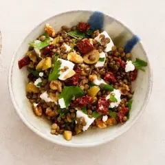 Insalata di lenticchie estiva con feta, pomodori secchi, olive e noci. Fresca e saporita, perfetta per un pasto leggero.