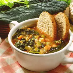Una ciotola fumante di zuppa di cavolo nero, con pane tostato e fagioli, pronta per essere gustata.