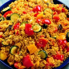 Un piatto colorato di cous cous con verdure miste: peperoni rossi e gialli, zucchine e melanzane. Una deliziosa ricetta cous cous.