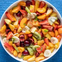 Una colorata macedonia di frutta fresca, con fragole, kiwi, pesche, banane e ciliegie, pronta per essere gustata.