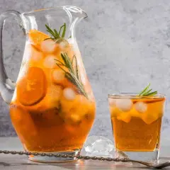 Rinfrescante freddo fatto in casa con arancia e rosmarino, servito in caraffa e bicchiere con ghiaccio.