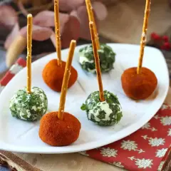 Sfere di ricotta al forno, alcune ricoperte di erbe fresche, altre di paprika, infilzate con grissini.