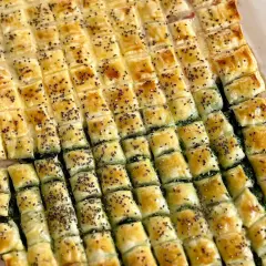 Pasticcio di pasta sfoglia rettangolare con ripieno verde, tagliato a quadretti e cosparso di semi. Un'idea su come farcire pasta sfoglia rettangolare.