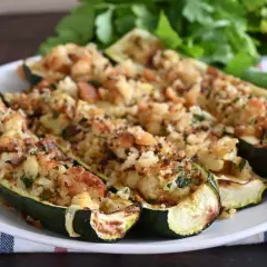 Zucchine ripiene velocissime, dorate e croccanti, servite su un piatto bianco con un contorno di prezzemolo fresco.