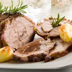 Succulento arrosto di vitello, affettato e servito con patate arrosto e rametti di rosmarino.