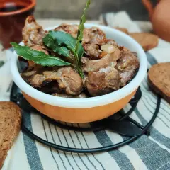 Durelli di pollo saporiti in ciotola, guarniti con foglie di alloro, accompagnati da fette di pane rustico.