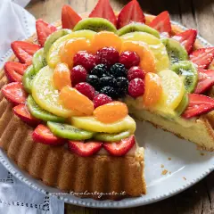 Una deliziosa crostata di frutta, con fragole, kiwi, mandarini, lamponi e mirtilli su una base di crema pasticcera.