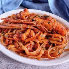 Un piatto invitante di linguine agli scampi, condite con un sugo rosso e guarnite con prezzemolo fresco.