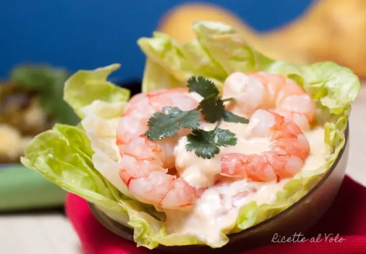 Gamberetti succulenti in salsa rosa cremosa, serviti su foglie di lattuga croccante. Un antipasto fresco e invitante.