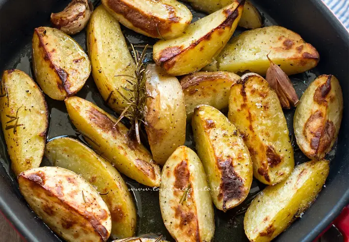 Patate al forno dorate e croccanti, condite con rosmarino e aglio, pronte per essere gustate.