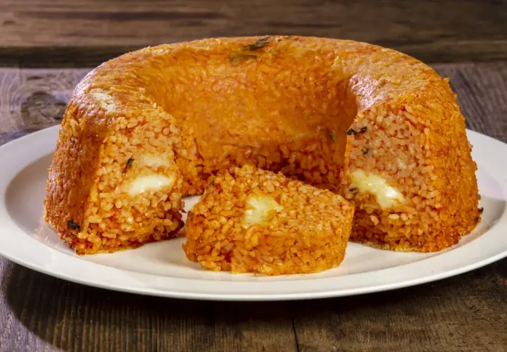 Un invitante timballo di riso, dorato e ripieno di formaggio filante, pronto per essere gustato.