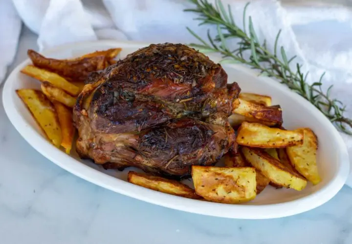 Stinco di maiale arrosto, dorato e succulento, servito con patate croccanti e rosmarino fresco.