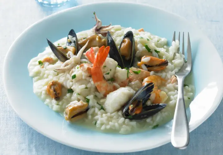 Un cremoso risotto alla pescatora, ricco di cozze, gamberi e calamari, pronto per essere gustato.