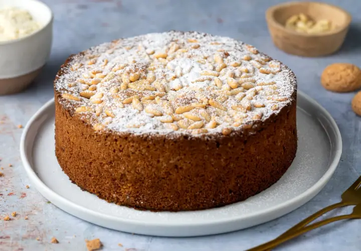 Torta rustica con farina di mandorle, guarnita con pinoli e zucchero a velo. Perfetta per ogni occasione.
