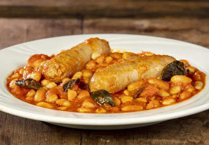 Salsiccia e fagioli in umido, un piatto rustico e saporito, servito su un piatto bianco.