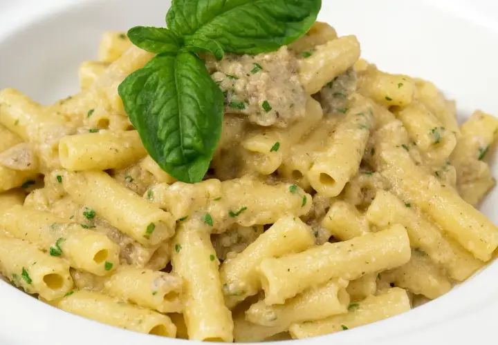 Un piatto invitante di pasta con melanzane in bianco cremosa, guarnito con basilico fresco.