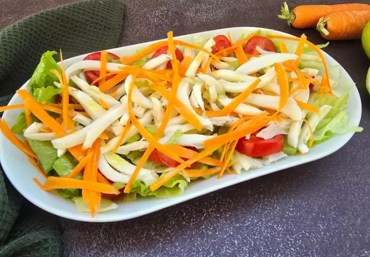 Deliziosa insalata di seppie con lattuga croccante, carote julienne e pomodorini freschi. Un piatto leggero e saporito.